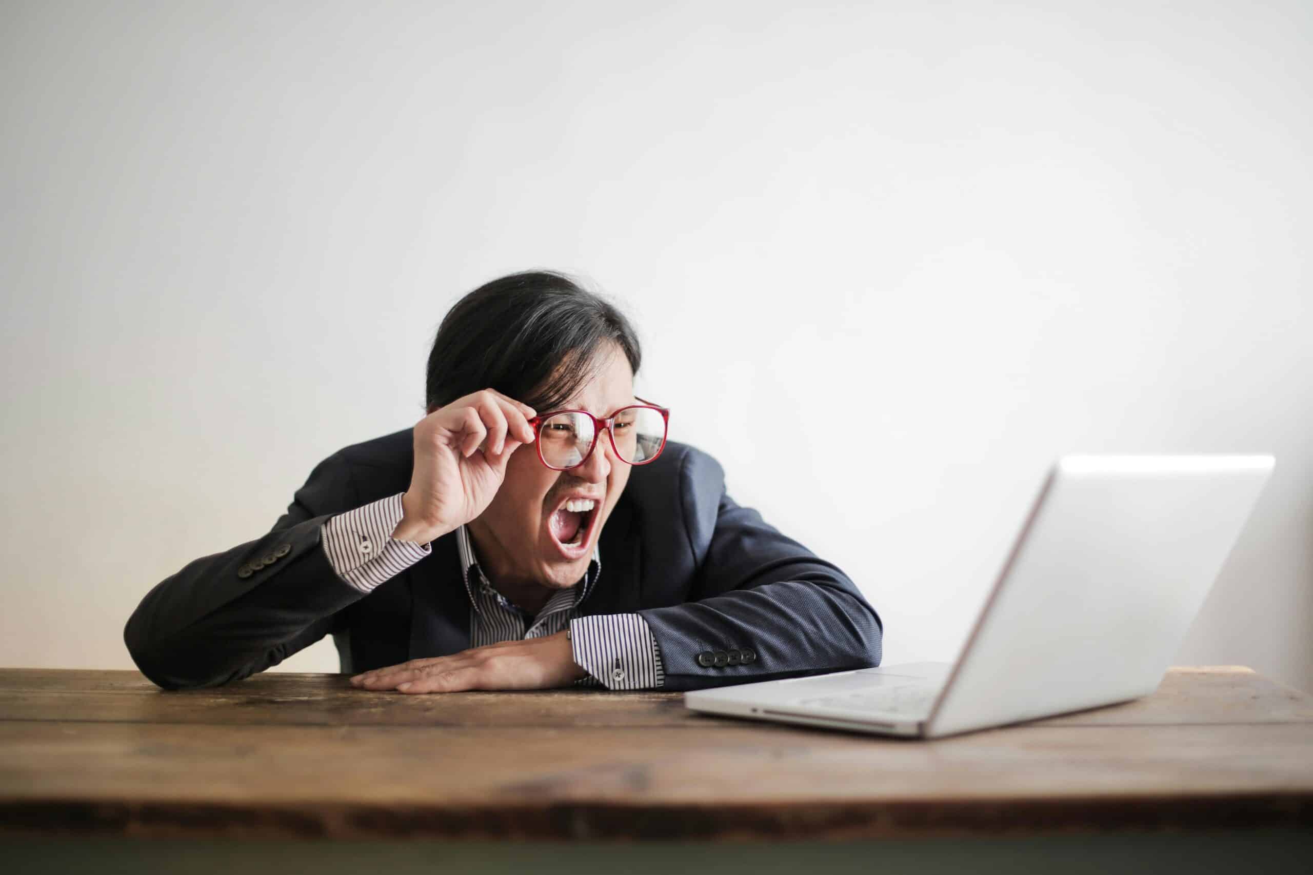 Frustrated businessman yelling at laptop screen