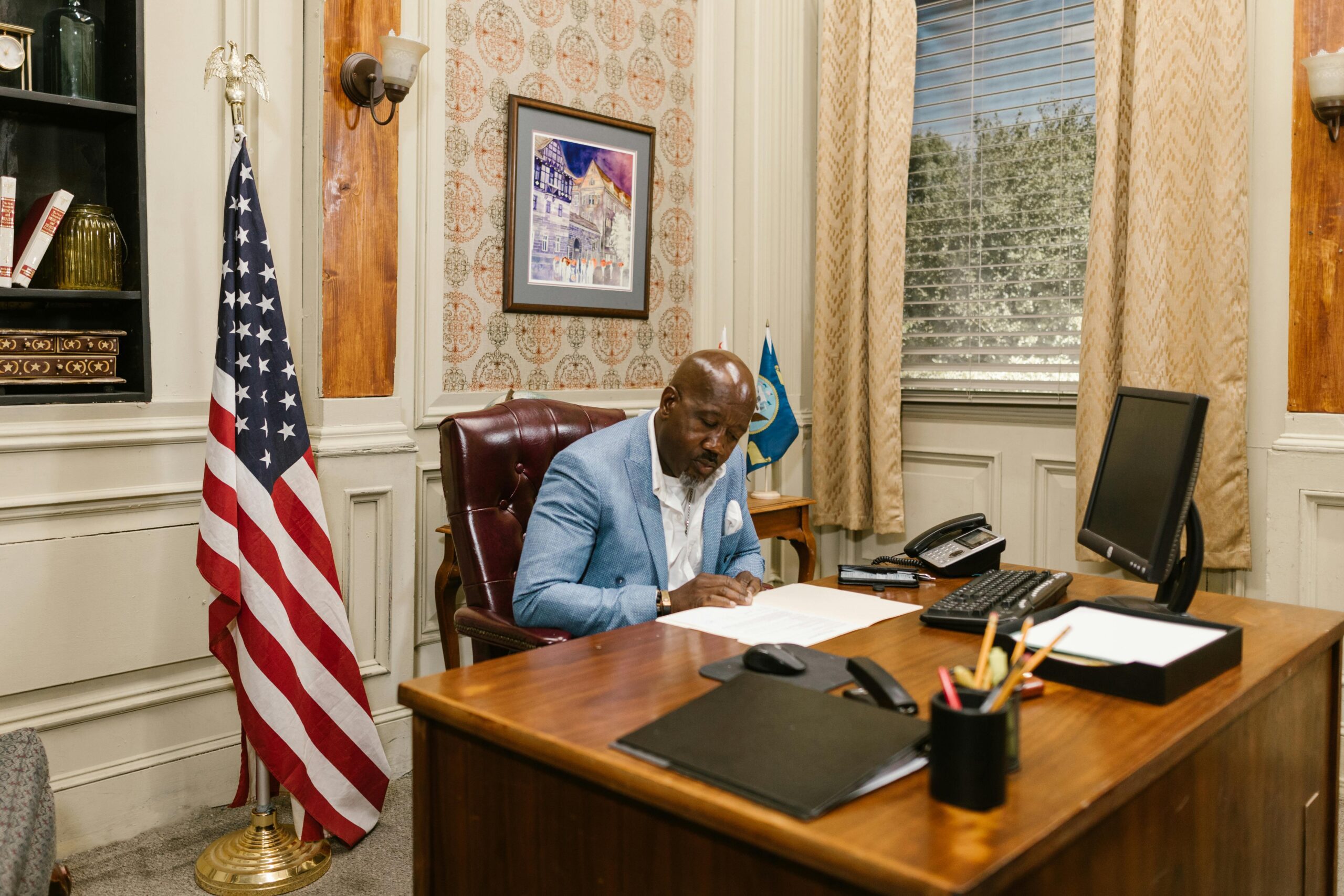 Man in blue suit working at desk with American flag