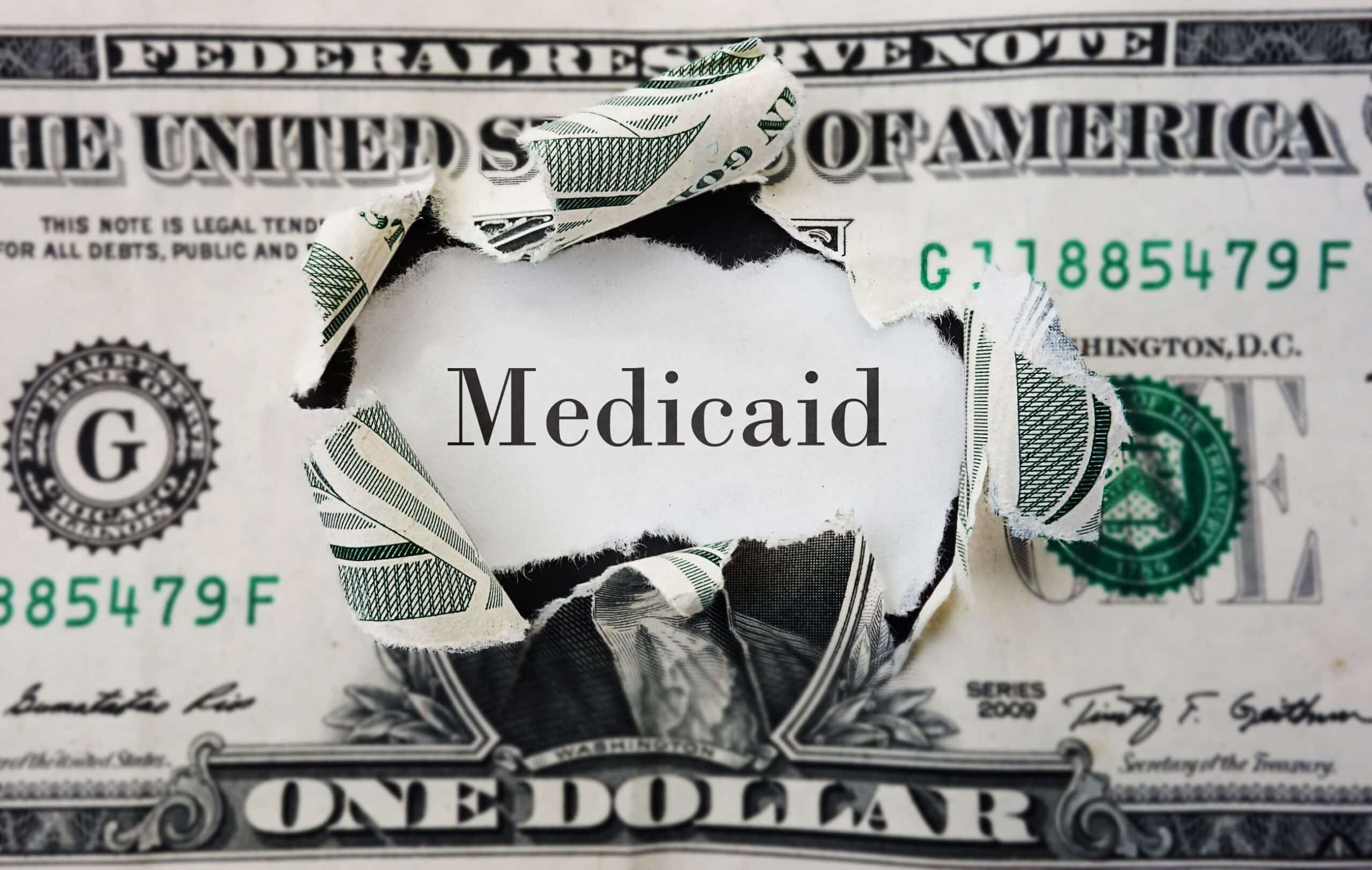 Torn dollar bill with 'Medicaid' text overlay