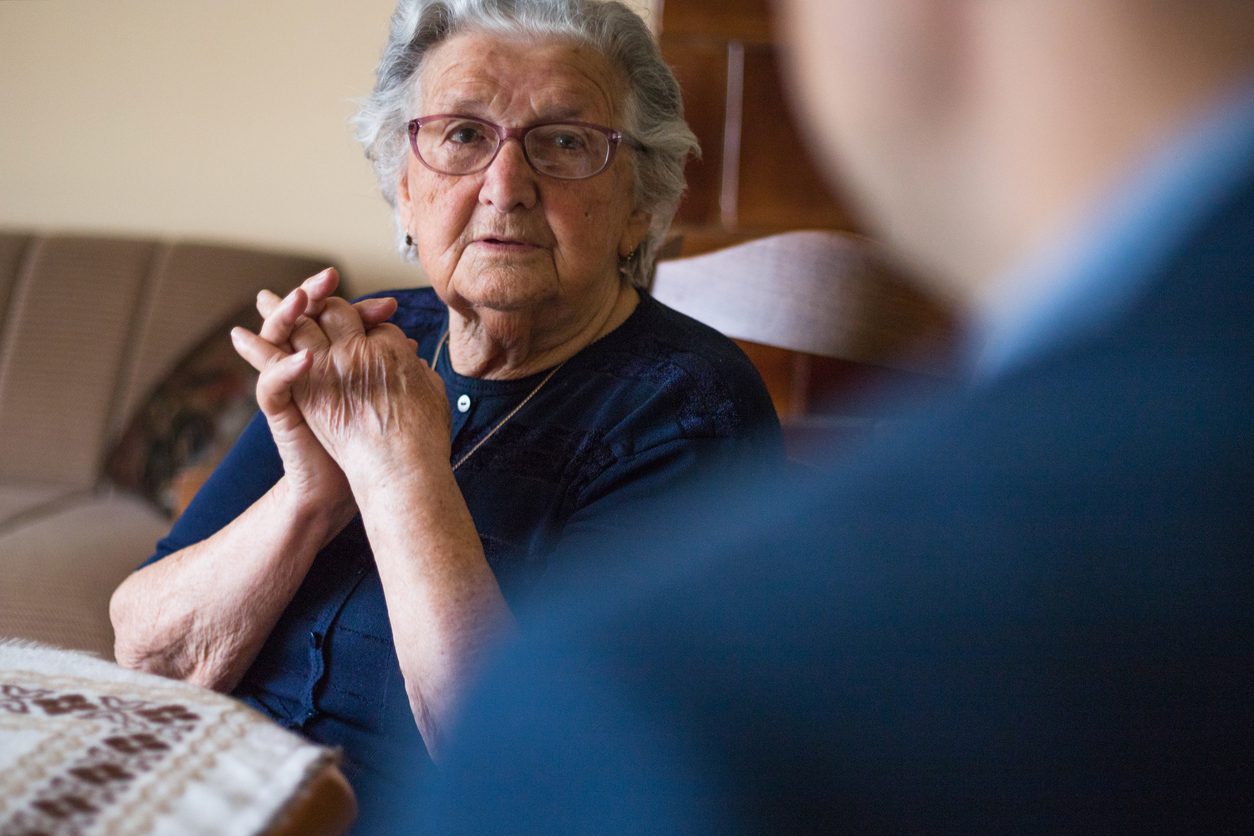 Elderly woman listening intently in a conversation.