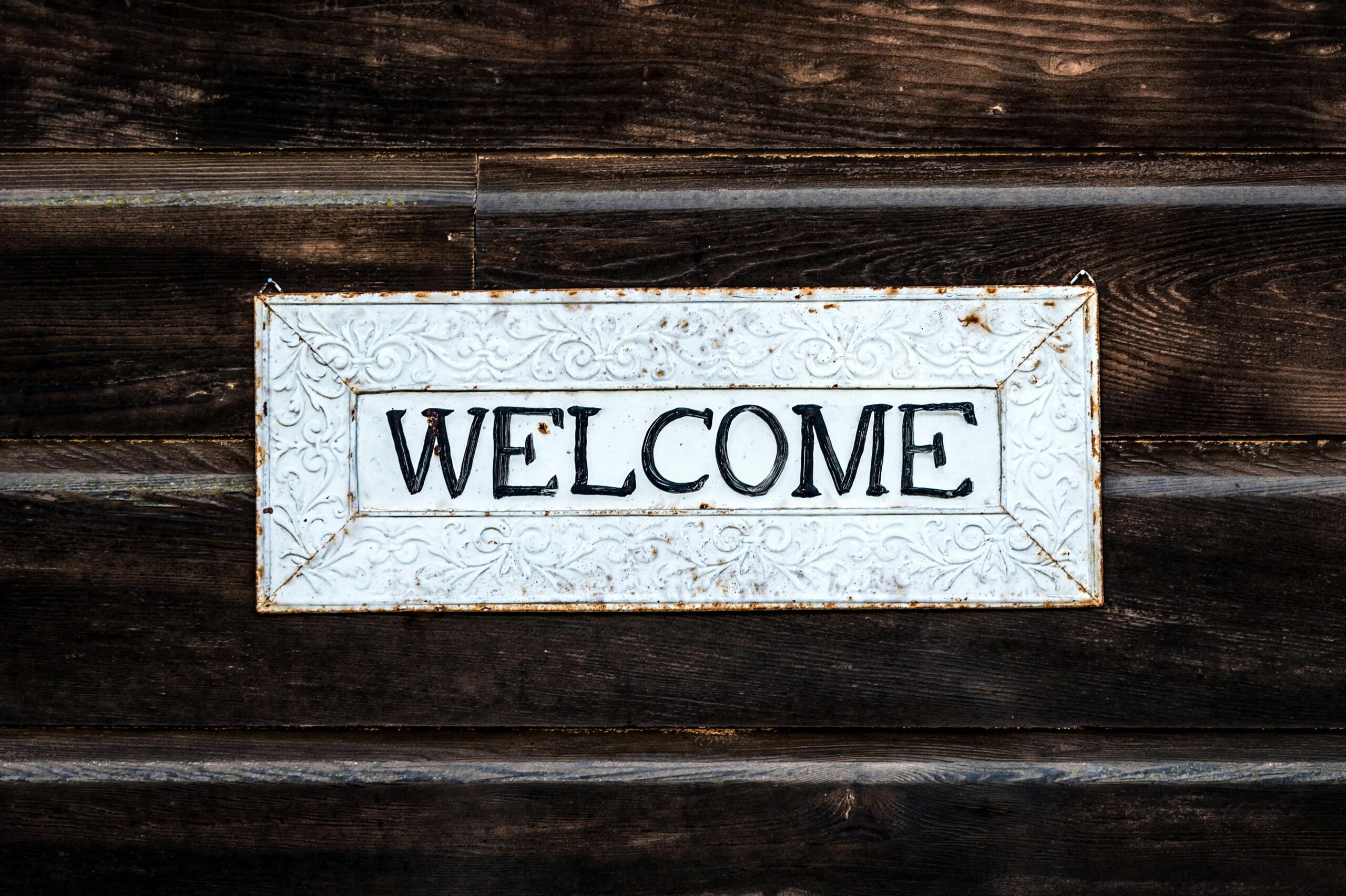 Vintage white 'WELCOME' sign on dark wooden background