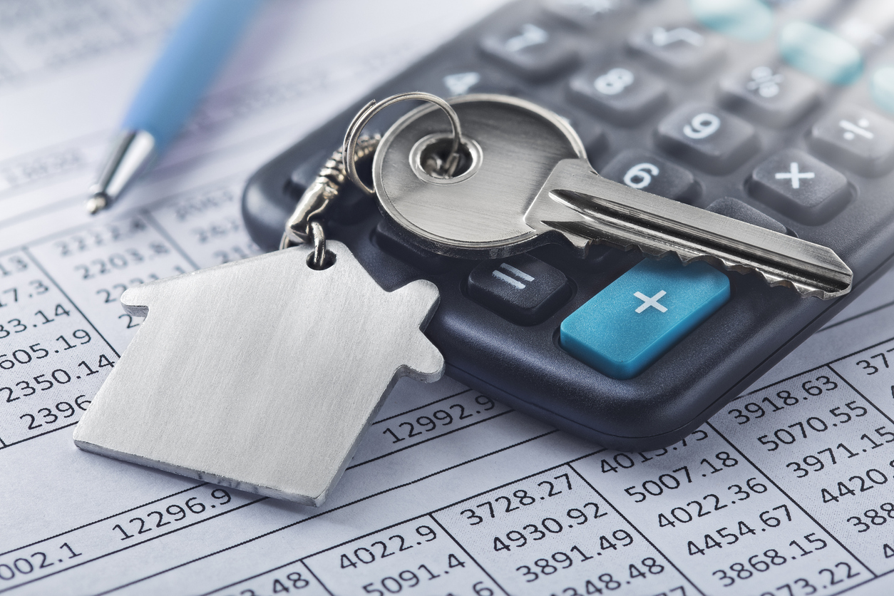 House key on calculator over financial documents