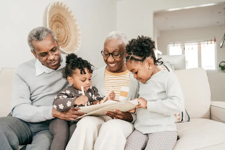 Grandparents reading with grandchildren on sofa