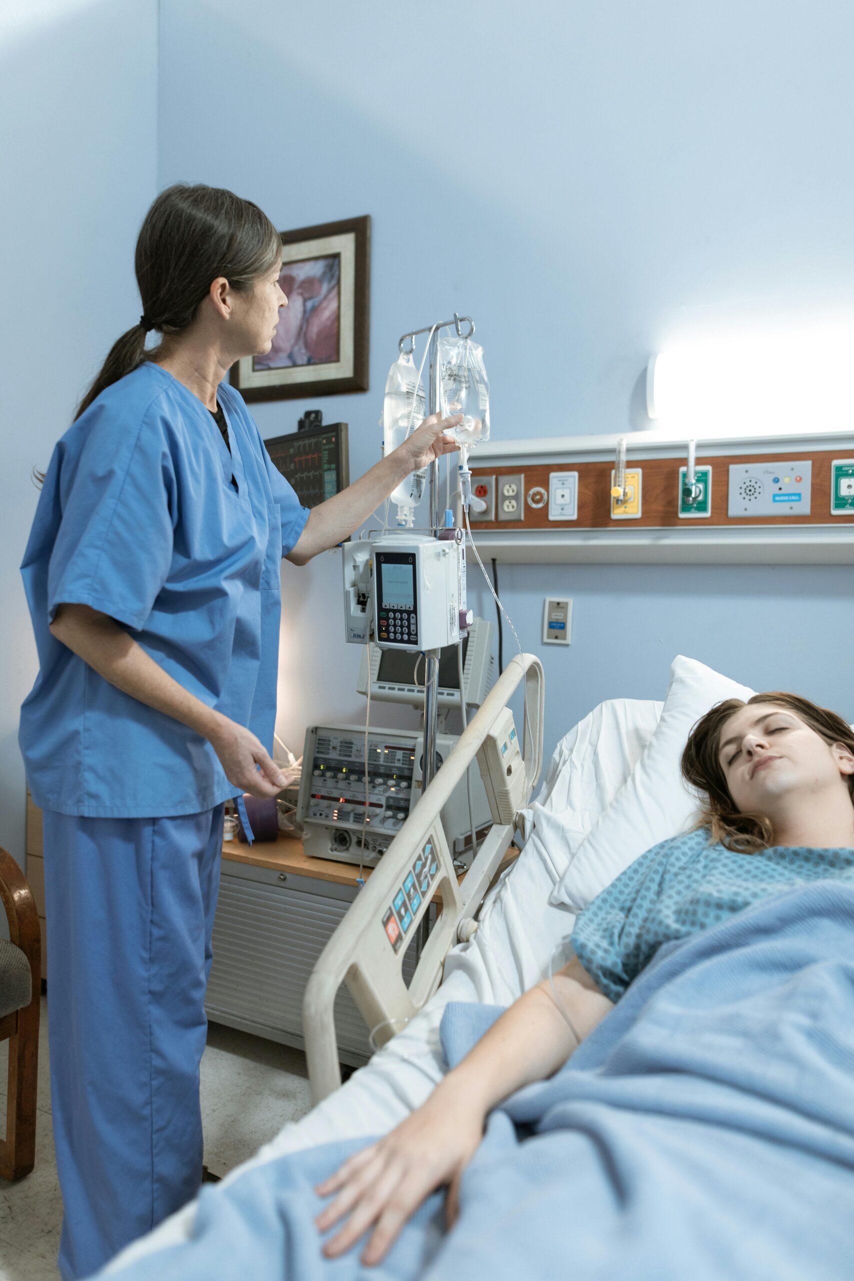 Nurse adjusting IV drip for patient in hospital bed