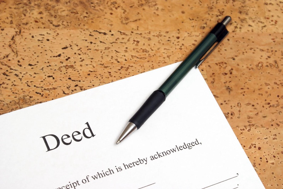 Pen on deed document on cork background